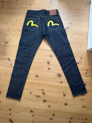 Evisu Raw Selvedge Jeans - Ett par råa selvedge jeans från märket evisu.               Väldigt bra kondition, endast använda ett fåtal gånger. Storlek är W28 L34                                                                                Midja: 38cm   Längd: 103cm  Benöppning: 16cm          