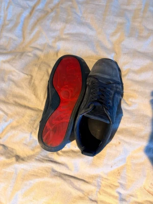 Mörkblå sneakers med röd sula - Snygga mörkblå sneakers med ovandel i mockaliknande material och matchande blå skosnören. Skorna har en unik röd sula som sticker ut och ger en cool kontrast. Klassisk låg modell med rund tå och diskret design.