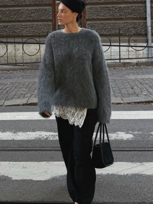 Grå fluffig stickad tröja i alpackaull - Mysig grå stickad tröja med fluffig textur och avslappnad passform. Nypris är 849kr. Tröjan har långa ärmar och rund halsringning, perfekt för lager på lager och en trendig look. Passar till både jeans och kjol för en cool vardagsstil.