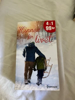 Minnen för livet antologi - En pocketbok med titeln 'Minnen för livet', en antologi med fyra berättelser av Fiona McArthur, Amy Andrews, Lucy Clark och Barbara Hannay. Omslaget visar två personer i vinterkläder som går i snön med en träkälke. Utgiven av Harlequin.