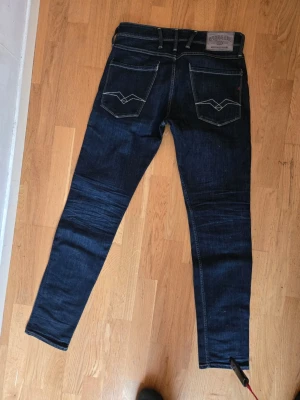 Mörkblå smala jeans med kontrastsömmar - Snygga mörkblå jeans med smal passform och vita kontrastsömmar. Jeansen har klassiska fem fickor. Mycket fint skick W31 L32