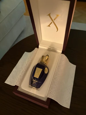 Xerjoff Torino 21 parfym 50ml - Lyxig parfym från Xerjoff i elegant mörkblå glasflaska med gulddetaljer och exklusiv förpackning. Flaskan har en unik form och pryds av en guldfärgad etikett samt lock. Doften heter Torino 21 och flaskan rymmer 50 ml. Så gott som ny använts ett fåtal sprut 