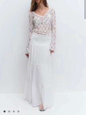 OANVÄND vit kjol från Gina Tricot  - Säljer en vit långkjol med bred smock i midjan och flera volangdetaljer. Kjolen är från Gina Tricot. Den är aldrig använd.