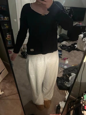 Svart långärmad topp  - Mysig loungewear med en svart långärmad topp med rund hals och liten spetskant samt ett dekorativt märke framtill. Perfekt för chill dagar hemma.