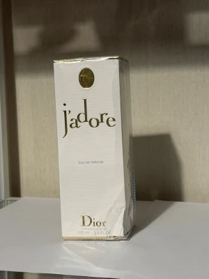 J'adore Eau de Parfum 100 ml från Dior - J'adore Eau de Parfum från Dior i elegant vit och guld kartong. Flaskan rymmer 100 ml och doften är känd för sin lyxiga, blommiga karaktär. Perfekt för dig som vill ha en ikonisk och feminin parfym i samlingen.