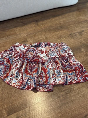 Mönstrad skort från SHEIN - Superfin skort från SHEIN med färgglatt paisleymönster i rött, blått och vitt. Modellen har volangig kjol med shorts under och resår i midjan för extra komfort. Perfekt för dig som gillar boho-vibe och vill ha något bekvämt men ändå snyggt.