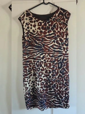 Ärmlös klänning med leopardmönster - Cool ärmlös klänning med leopard- och zebramönster i brunt, svart och vitt. Rak passform och rund halsringning. Perfekt för dig som vill sticka ut med ett djurmönstrat plagg.