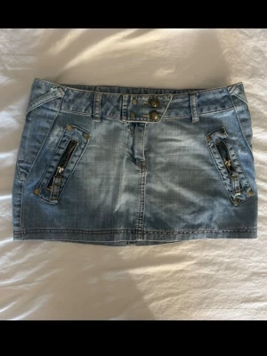 Mini jeanskjol - Säljer en kort ljusblå jeanskjol med guld detaljer, aldrig använt!