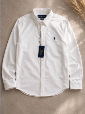 Vit skjorta från Polo Ralph Lauren - Klassisk vit skjorta från Polo Ralph Lauren med button-down krage och broderad logga på bröstet. Skjortan har långa ärmar, knappar framtill och är tillverkad i mjuk bomull. Perfekt för en clean och stilren look.