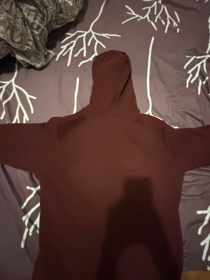 Mörkröd hoodie från Lacoste med huva - Säljer en snygg mörkröd  hoodie från Lacoste med klassisk krokodillogga på bröstet. Hoodien har huva med dragsko och en stor magficka framtill. Perfekt för dig som gillar stilrena och bekväma plagg.