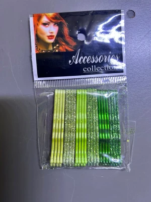 Två paket hårnålar i glitterfärger - Säljer två paket hårnålar från Accessories Collection. Ena paketet innehåller hårnålar i olika nyanser av grönt och gult med glitter, det andra i beige, guld, brons och brunt med glitter. Perfekta för att piffa till frisyren och hålla håret på plats. 39kr/paket/24st 