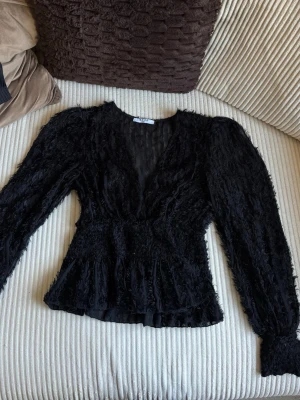 Långärmad festtopp/tröja - Svart tröja med svart fringe detaljer, väldigt fin! Endast använd en gång. Har resor i midjan