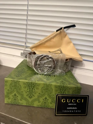 Gucci bälte  - Snyggt bälte från Gucci med klassiskt GG-spänne i silverfärg. Bältet har ett beige och brunt mönster med Guccis ikoniska logga och är tillverkat i skinn. Perfekt accessoar för att lyfta din outfit.