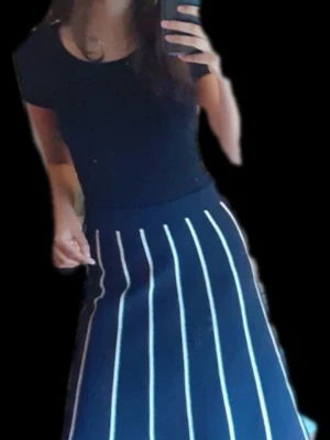 Svart kortkjol med vita ränder - Unik design navy midikjol med vita lodräta ränder. Från Lindex, Vintage design. Kjolen har en lätt utställd form, vilket ger en modern och stilren look. Perfekt att matcha med en enkel topp eller 90s röd top för en trendig outfit. Storlek XS men funkar för S o M. Ny skick med prislapp. 