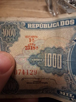 Brasiliansk 1000 Cruzeiros sedel - Säljer en gammal brasiliansk 1000 Cruzeiros sedel med blå och beige färg, detaljerade mönster och röda serienummer. Texten 'REPÚBLICA DOS' och 'CAIXA DE AMORTIZAÇÃO' syns tydligt. Perfekt för samlare av utländska sedlar.