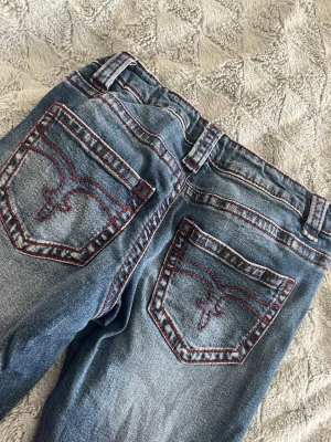 Blå jeans med röd söm från gina tricot! - Säljer ett par blå jeans från gina tricot med snygga röda kontrastsömmar och broderade bakfickor. Jeansen är i bra skick och endast andvända några gånger!