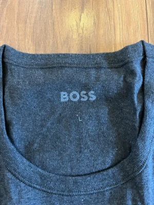Svart t-shirt från BOSS - En stilren svart t-shirt från BOSS med rund halsringning och diskret logga på bröstet. Tillverkad i mjuk bomull för en bekväm känsla. Perfekt basplagg för en enkel och snygg look.