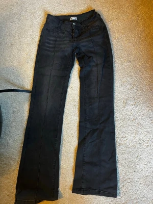 Svarta bootcut jeans med fickdetaljer - Snygga svarta bootcut jeans med dekorativa sömmar och knappar på bakfickorna. 
