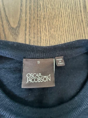 Mörkblå tröja från Oscar Jacobson - Klassisk mörkblå rundhalsad tröja från Oscar Jacobson. Tillverkad i Italien med ribbade muddar vid ärmslut och nederkant. Perfekt för en stilren och enkel look. Materialet ser ut att vara mjukt och tunt, troligen ull eller bomull.