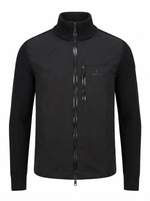 Svart cardigan jacka från Moncler - Stilren svart cardigan jacka från Moncler med stickade ärmar och hög krage. Jackan har dragkedja framtill, bröstficka med dragkedja och diskret Moncler-logga på bröstet samt ärmen. Perfekt för dig som gillar en clean look.