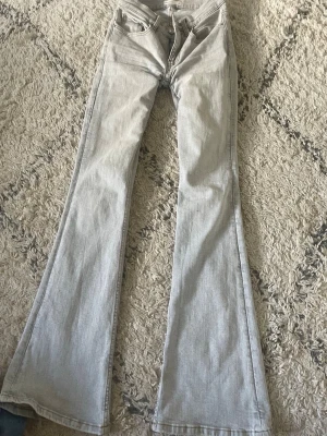 Ljusblå utsvängda jeans - Säljer ett par ljusblå jeans med utsvängda ben och klassisk femficksdesign. Jeansen har hög midja och är tillverkade i denim med en snygg tvätt. Perfekta för dig som gillar retrostil och vill ha ett par trendiga byxor i garderoben.