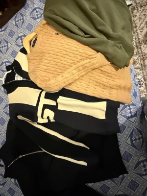 4 pack tröja - Kabelstickad tröja i beige från Polo Ralph Lauren med rund halsringning och klassisk blå logga broderad på bröstet. Tröjan har en tidlös design med ribbade muddar och är perfekt för lager-på-lager-stil.