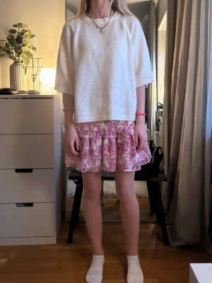 Vit trekvart stickad tröja - Vit oversized stickad tröja med halvlånga ärmar och rund halsringning. Tröjan har en enkel och clean design som passar perfekt till lager på lager och ger en avslappnad look.