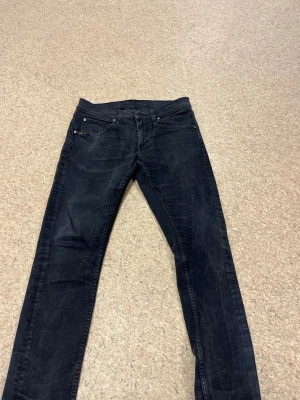 Svarta/gråa slim fit jeans - Snygga svarta jeans i slim fit-modell med klassisk femficksdesign och diskreta slitningar. Jeansen har normal midja och raka ben. Perfekta för en stilren och avslappnad look. Storlek 31/32
