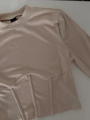 Beige ribbed long sleeve top  - Beige ribbed long sleeve top   Size: M Condition: new, never worn  Details: fitted ribbed top with corset-style seams, soft stretchy fabric, flattering fit  💰 Price: 150kr  📦 Fast shipping / meet-up possible Message me if interested 💌