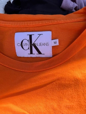 Calvin Klein T-shirt storlek M  - En orange Calvin Klein T-shirt storlek M. Se bilder för skick. Använd fåtal gånger. 
