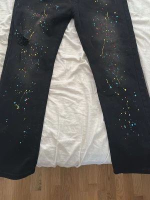 Svarta jeans med färgstänk - Säljer mina svarta jeans med färgstänk i gult, blått och rött.  Materialet är denim