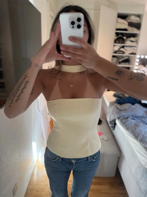 Ljusgul axelbandslös topp med choker - Trendig ljusgul axelbandslös topp med matchande choker-detalj runt halsen. Snygg, figurnära passform som ger en clean och modern look. Perfekt att styla med jeans eller kjol för en cool vibe. Står ingen storlek men passa mig som bruka ha S