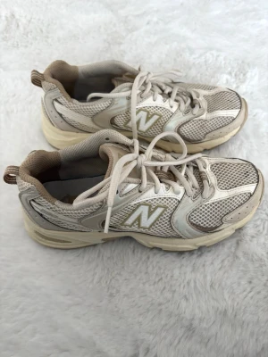 New Balance 530 beige - Sneakers från New Balance i modellen 530. Vita med beige detaljer i storlek 38, fint skick. 