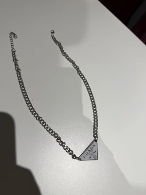 Prada white & silver necklace - No box! Unisex model. ✅ Perfect condition  – Brand new, never worn  💯 100% Authentic products only 📦 Fast shipping ♻️ Shop sustainably, look sharp.  REMINDER: Items can be used and please note that we only resell used clothes we buy online (some are brand new).   We will always tell our customers before buying if item has stains or is damaged. Returning is always possible  Bought in here. If you have anything authentic to sell, let us know because we also buy and sell on here🙂  Thank you!