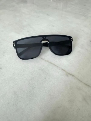 Svarta LV solglasögon med kryss - Gå på stranden i stil. Med dessa snygga solglasögon skyddar du ögonen i stil, Helt nya svarta LV