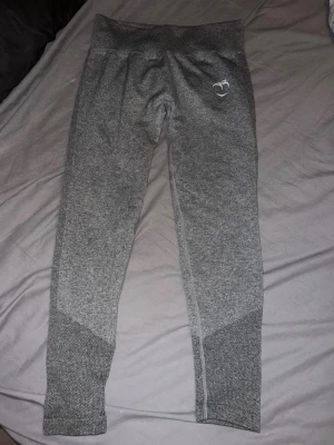 Peach tights - Snygga grå  tights från Peach med hög midja och diskret logga på vänster höft. Materialet är stretchigt och andas, perfekt för träning eller gym. Tightsen har en snygg kontrastdetalj vid bensluten för extra stil. 