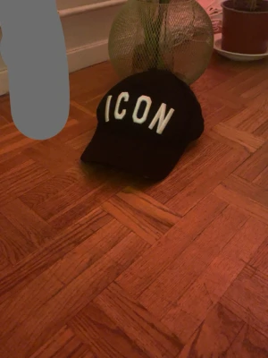 Svart Dsquared2 ICON keps - Svart keps från Dsquared2 med stor vit 'ICON'-text framtill och broderad logga baktill. Justerbar rem med metallspänne. Snygg och stilren accessoar som lyfter din outfit.