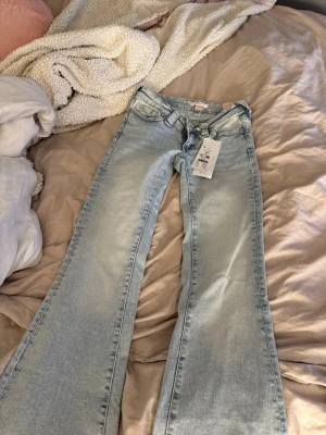 Ljusblå bootcut jeans från Gina tricot  - Säljer ett par ljusblå bootcut jeans från Gina tricot med klassiska W-broderade bakfickor. Jeansen har låg midja, bälteshällor och är tillverkade i mjuk denim. Perfekta för dig som gillar retrostil och vill ha ett par riktigt snygga jeans.💗