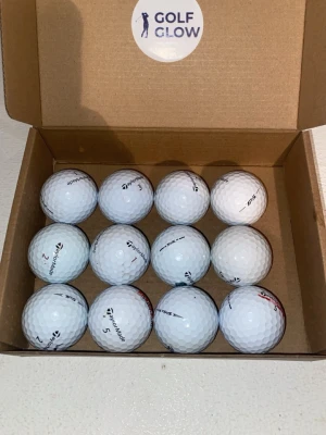 Taylormade TP5 12-pack  - Säljer ett set med 12 vita golfbollar från TaylorMade, levererade i en brun kartong med Golf Glow-logga. Bollarna har klassisk dimple-design och är märkta med TaylorMade-loggan. Perfekt för dig som vill fylla på golfbagen inför säsongen.