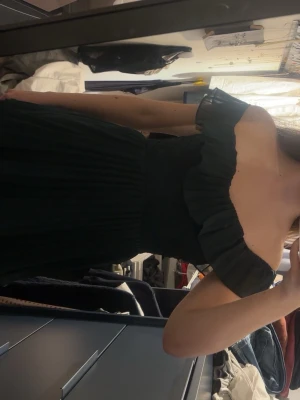 Mörkgrön offshoulder långklänning - Snygg mörkgrön långklänning med volanger och offshoulder-modell. Klänningen har flera lager i kjolen, en jättefin balklänning.