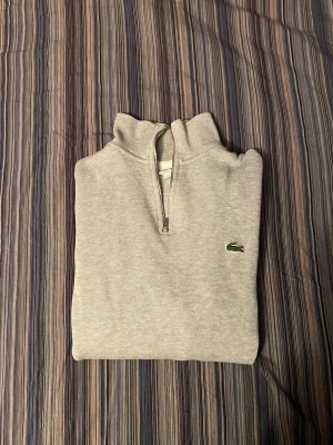Lacoste quarter zip (äkta) - Säljer min gråa Lacoste quarter zip i storlek S. Den är använd men är i mycket bra skick med inga defekter. Hör av er ifall ni är intresserade eller har frågor!
