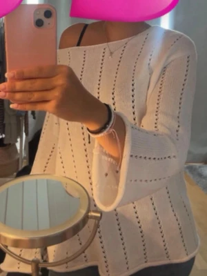 Vit stickad tröja med hålmönster - Säljer en vit stickad tröja med hålmönster och utsvängda ärmar. Tröjan har en lös passform och båtringad hals. Perfekt för dig som gillar en avslappnad men ändå stilren look.