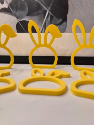 Gula servettringar med kaninöron 6st - Säljer ett set med gula  servettringar i form av kaninöron. De är tillverkade i plast och har en lekfull, rund design med utstickande öron. Perfekta för att ge dukningen en fin och unik touch.