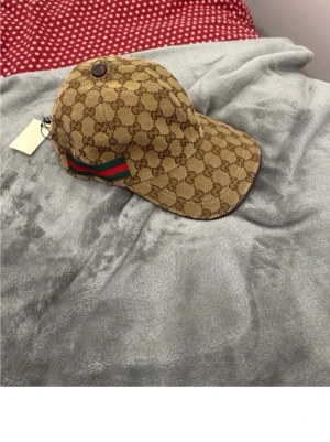 Beige Gucci keps - Säljer en Biege Gucci keps, helt oanvänd med etikett fortfarande på. Jag vill sälja denna eftersom den inte passar mig. Är öppen för pris förslag