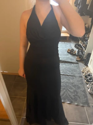Svart långklänning med halterneck - Säljer en jättefin maxiklänning från NA-KD med flowy passform i satinliknande material. Klänningen har en knytbar halterneck och en öppen rygg som ger en elegant och feminin look. Vågig nederfåll och en dold dragkedja i sidan. Perfekt till fest, sommar eller semester🌟  📏 Storlek: 36 ✨ Skick: Helt ny – aldrig använd, lappen sitter kvar och originalförpackning