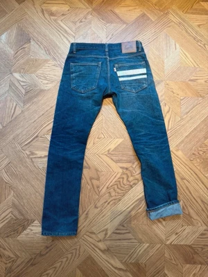 Momotaro jeans - Säljer ett par riktigt snygga momotaro jeans i storlek 31 men är i vintage/japanska storlekar så kolla istället på måtten för en bättre bild av storleken. Hör gärna av dig vid frågor och funderingar! Mått: Midja - 41 cm. Längd - 99,5 cm. Benöppning - 17,5 cm.