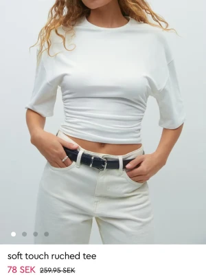 Vit croppad topp med scrunch - Slutsåld i alla storlekar. Trendig vit croppad topp med scrunch i sidorna och trekvarts ärmar. T-shirten har en tight passform och är tillverkad i ett mjukt material som sitter skönt mot kroppen. 