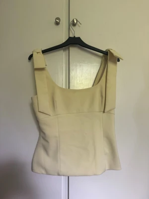 Trendigt gul Zara topp med rosetter - Gullig gul topp från Zara, storlek S, med rosetter på axlarna och osynlig dragkedja. Några fläckar på insidan och en som syns väldigt lite på framsidan. Kan skicka fler bilder😊💕 Annars inga defekter