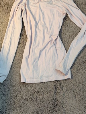 Ljusrosa långärmad topp med strass - Snygg ljusrosa långärmad topp med strassdetaljer och dekorativa band vid halsringningen. Toppen har en feminin passform och är tillverkad i mjuk bomull, perfekt för dig som gillar en enkel men ändå trendig stil.(Köpte den för 1300kr så passa på att köp för bra pris)‼️. (STORLEK 158-164) passar från xXXS-s (kanske m). Djup ringning i ryggen med band.Dekorerad med kristaller