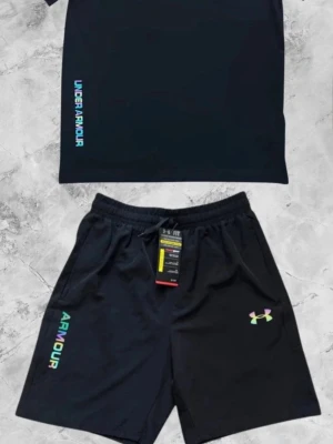 Svart träningsset från Under Armour - Snyggt svart träningsset från Under Armour med t-shirt och shorts. Båda plaggen har logga och text i regnbågsfärger. Shortsen har resår i midjan och sidofickor. Perfekt för gym eller löpning. Pris kan diskuteras vid snabb affär